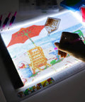 Diamond Painting Light Pad Kit A4 With LED Tracing Box And 5D Tool Set in use for a partial drill art scene, hand applying diamonds
