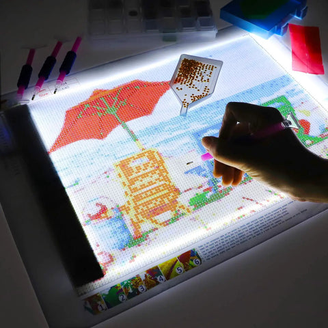 Diamond Painting Light Pad Kit A4 With LED Tracing Box And 5D Tool Set in use for a partial drill art scene, hand applying diamonds