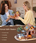 Two women admiring assembled Hawaiian Vacation Beach House 3D Wooden Puzzle Kit With LED Light For Adults, 187 Pieces DIY Model Building Kit.