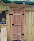 Wooden shed door with Six Pack 5 Inch T Shape Strap Hinges With Screws in classic black, outdoor-rated hardware installed.