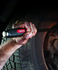 Using Dominator Pry Bar Set Five Piece Curved Pry Bars With Ergonomic Dual Composite Handles near a car wheel for leverage.