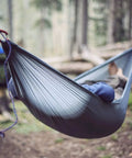 Individual relaxing in Go-To Nano 7 Ultra Light Hammock For Camping And Travel With Ripstop Nylon in forest setting