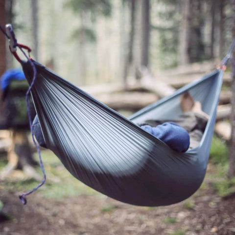 Individual relaxing in Go-To Nano 7 Ultra Light Hammock For Camping And Travel With Ripstop Nylon in forest setting