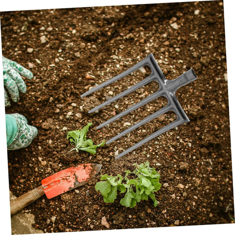 Heavy Duty Steel Farm Fork With Four Prongs for Soil Loosening and Turning, shown on garden soil next to hand trowel