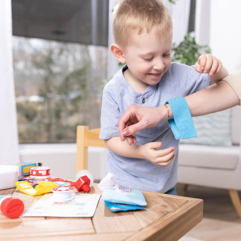 Child playing with Get Well First Aid Kit Play Set For Kids With 25 Realistic Medical Tools For Pretend Doctor Play on table.