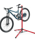 Ultralight Pro Bike Repair Stand travel ready work stand with tripod base, holding a mountain bike, red aluminum, secure clamp shown