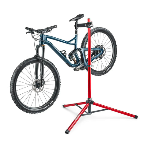 Ultralight Pro Bike Repair Stand travel ready work stand with tripod base, holding a mountain bike, red aluminum, secure clamp shown