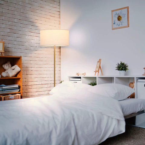 Quinn LED Floor Lamp With Drum Shade in bedroom corner, brass gold finish, beside bed and shelves