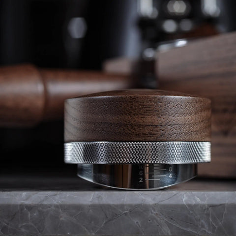 Side view of Walnut 58.35mm Espresso Distribution Tool, Adjustable Depth, Stainless Steel Leveler For 58mm Portafilters on a counter.