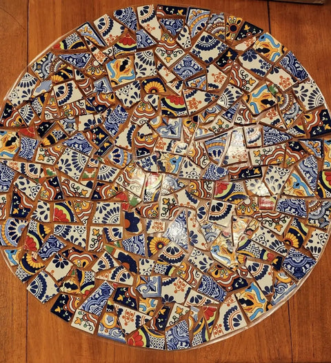 Circular mosaic tabletop with 10 Pound Bundle Of Broken Mexican Talavera Tiles For Mosaic Projects And DIY Decor, colorful patterns visible.