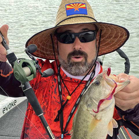 Angler holding fish and fishing rod with Spartacus II Baitcasting Reel in Stryker Green, showcasing low-profile design on lake.