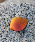 Fire Orange Polarized PRO Plus Replacement Lenses For Electric Stacker Sunglasses resting on a granite surface, showcasing lens color and design.