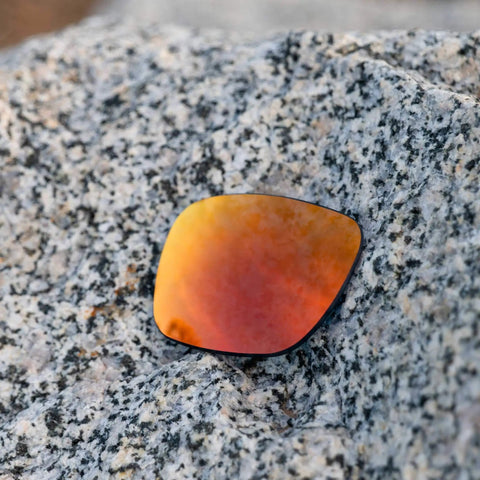 Fire Orange Polarized PRO Plus Replacement Lenses For Electric Stacker Sunglasses resting on a granite surface, showcasing lens color and design.