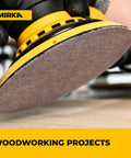 Close-up of 80 Grit 5 Inch Dust Free Mesh Sanding Discs with Hook and Loop for orbit sander in use on wood surface.