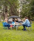 Family enjoying outdoor meal near Zeta C6 Pro Six Person Instant Cabin Tent with 60 Second Setup, khaki, in forest setting.