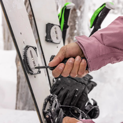 Hand adjusts snowboard binding with Suspension NXT 15 In 1 EDC Multitool with needle nose pliers in snow.
