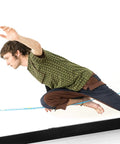 Person balancing on Slackhouse 3.0 Indoor Slackline Structure for gym and home training with steel rack and polyester webbing.