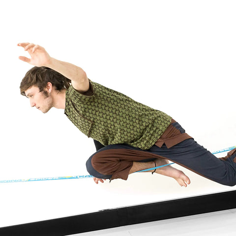 Person balancing on Slackhouse 3.0 Indoor Slackline Structure for gym and home training with steel rack and polyester webbing.