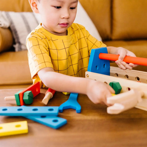 Child playing with Take Along Tool Kit Wooden Construction Toy Set For Little Builders With 24 Pieces Including Hammer, Wrench, Boards