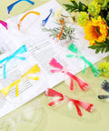 Colorful assortment of 100 Pack Kids Safety Glasses Bulk Set for Lab, Sports, and Shooting displayed with flowers and book