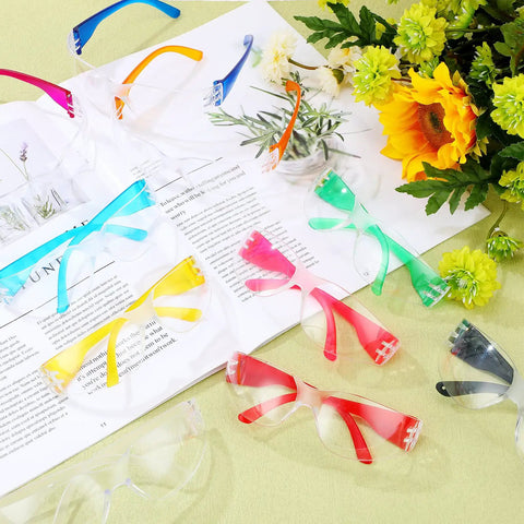 Colorful assortment of 100 Pack Kids Safety Glasses Bulk Set for Lab, Sports, and Shooting displayed with flowers and book