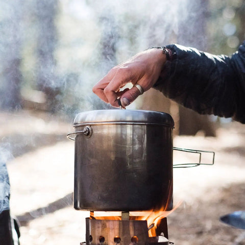 Pot 4000 Stainless Steel Camping Pot for outdoor cooking on campfire with foldable handles in use in forest setting.