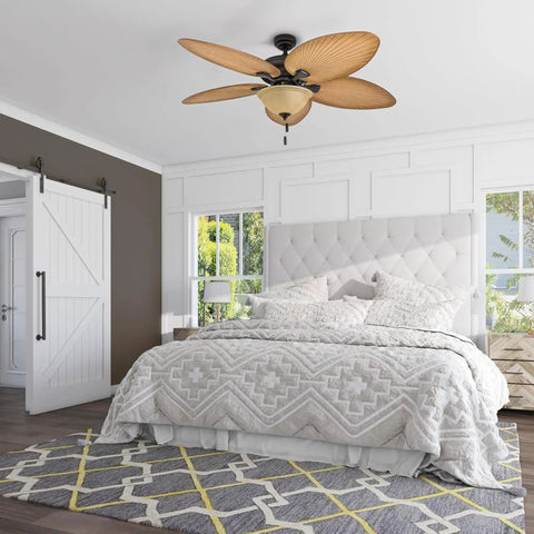 Palm Valley 52 Inch Tropical Ceiling Fan With Light installed in a bedroom, featuring five palm leaf blades and a bronze finish.