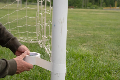 Person using White Duct Tape Roll 1.88 Inch By 20 Yards Heavy Duty For Repairs Crafting And Temporary Floor Marking Removable Cleanly Up To Three Weeks Not For Hardwood Or Direct Sunlight Single Roll on a soccer post outdoors.