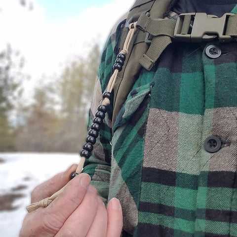 Close-up of hand using Pace Count Beads For Land Navigation Kit, Trail Ready Counter Beads For Hiking And Orienteering on backpack strap.