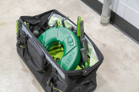 Reel X Stainless Steel Fishtape 240 Foot One Eighth Inch Wide in tool bag with green casing, for pulling cables and power lines.