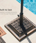 Heavy Duty 26 Pound Steel Patio Umbrella Stand With Bronze Finish Square Base Decorative Basket Weave Pattern Weather Resistant Resin Wind Resistant Fits 1.5 To 1.75 Inch Poles next to pool