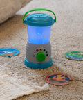 Durable Light And Sound Camping Lantern Toy With Six Color Modes and scene cards on carpet for kids' pretend play.