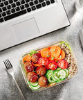 Glass Food Storage Set With 24 Pieces And Upgraded Snap Lock Lids For Meal Prep on table with salad near laptop and cutlery