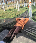 Person relaxing on Outdoor Triangular Hammock With Mesh Nylon, Portable 3 Point Design For Camping And Backyard Lounging.