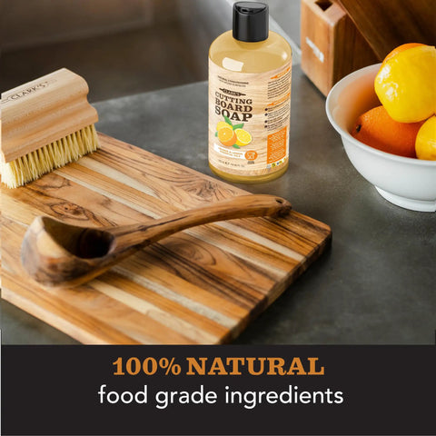 Three Step Cutting Board Care Kit With Soap Food Grade Mineral Oil And Wax For All Wood Boards Protects Against Cracking Warping And Stains Keeps Your Kitchen Looking Fresh And Natural Chemical Free with cutting board, soap, brush, and wooden spoon on counter.