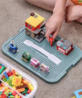 Child organizing Lego figures on Slick 3 Tier Stackable Brick Storage Organizer With Removable Grid Trays For Lego Pieces.