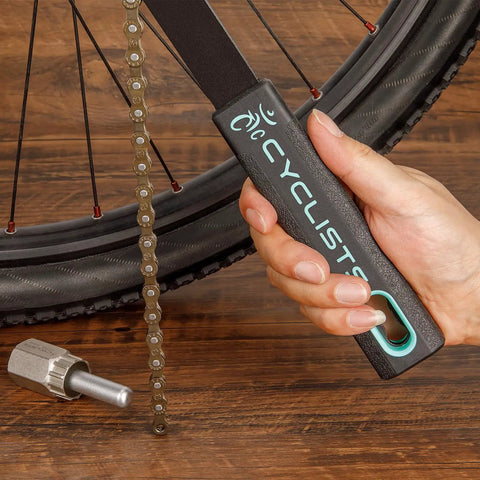 Hand holding chain whip from Pro Grade Cassette Removal Tool Kit With Chain Whip And Lockring Tool 5mm And 12mm Guide Pins Fits Shimano HG Freewheel Cassettes Easy Gear Maintenance For Quick Clean And Replacement near bicycle wheel.
