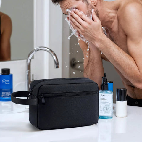Travel Hanging Toiletry Bag With Carry Handle, water-resistant black bag on a bathroom counter with toiletries, compact size.
