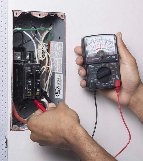 Person using GMT 318 Analog Multimeter With Six Functions And Fourteen Ranges Reads AC And DC Volts Up To 500V on circuit panel