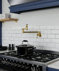 Wall Mount Pot Filler Faucet With 24 Inch Reach Pro Grade Dual Swivel Joints And Twin Handles Solid Brass Interior Stainless Steel Brushed Gold Finish Single Hole Install Wide Range Of Motion Dual Shut Off Valve over a black stove on a white backsplash