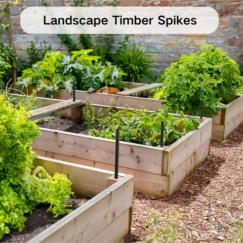 Raised garden beds with black stakes, labeled 'Landscape Timber Spikes', surrounded by greenery and brick wall.