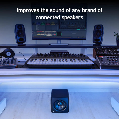 Compact Studio Subwoofer With ARC X Auto Calibration And 25 Hz Deep Bass, 6.5 Inch Driver under a studio desk with monitors