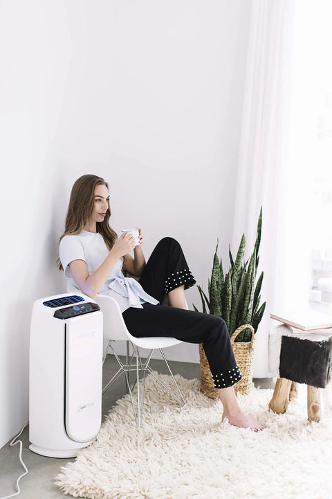 Woman relaxing next to PU4020 air purifier, uses Active Carbon Odor Filter For PU4020 Intense Pure Air Auto Purifier, kills bedroom odors.