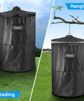 Portable Pop Up Privacy Tent For Camping And Emergencies, shown freestanding and hanging from a branch on grassy terrain.