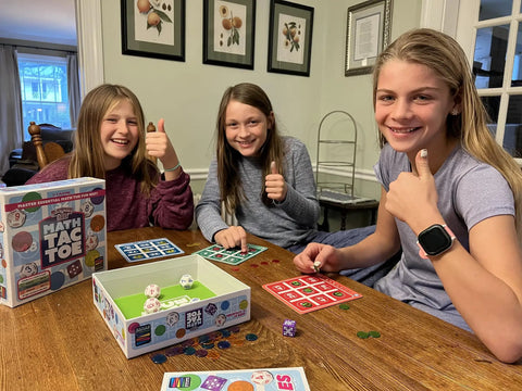 Three kids playing Play Smart Dice Math Tac Toe Game Sharpen Mental Math With A Fun Twist On A Timeless Classic Multilevel Math Bingo.