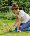 Woman using Stainless Steel Bent Angle Gardening Sickle Weed Scraper Hoe With Ergonomic Ash Wood Handle on grass