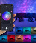 Person holding smartphone showing Galaxy Nebula Projector Light app control with LED starry sky in a home theater bedroom.