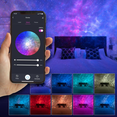 Person holding smartphone showing Galaxy Nebula Projector Light app control with LED starry sky in a home theater bedroom.