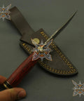Damascus Steel Hunting Knife With Rosewood Handle 8 Inch Full Tang Blade and leather sheath displayed on a table