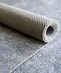 Rolled Ultra Slim Non Slip Rug Pad 2x3 Ft Felt And Rubber One Sixteenth Inch Thick for High Traffic Areas and Entryways on gray surface